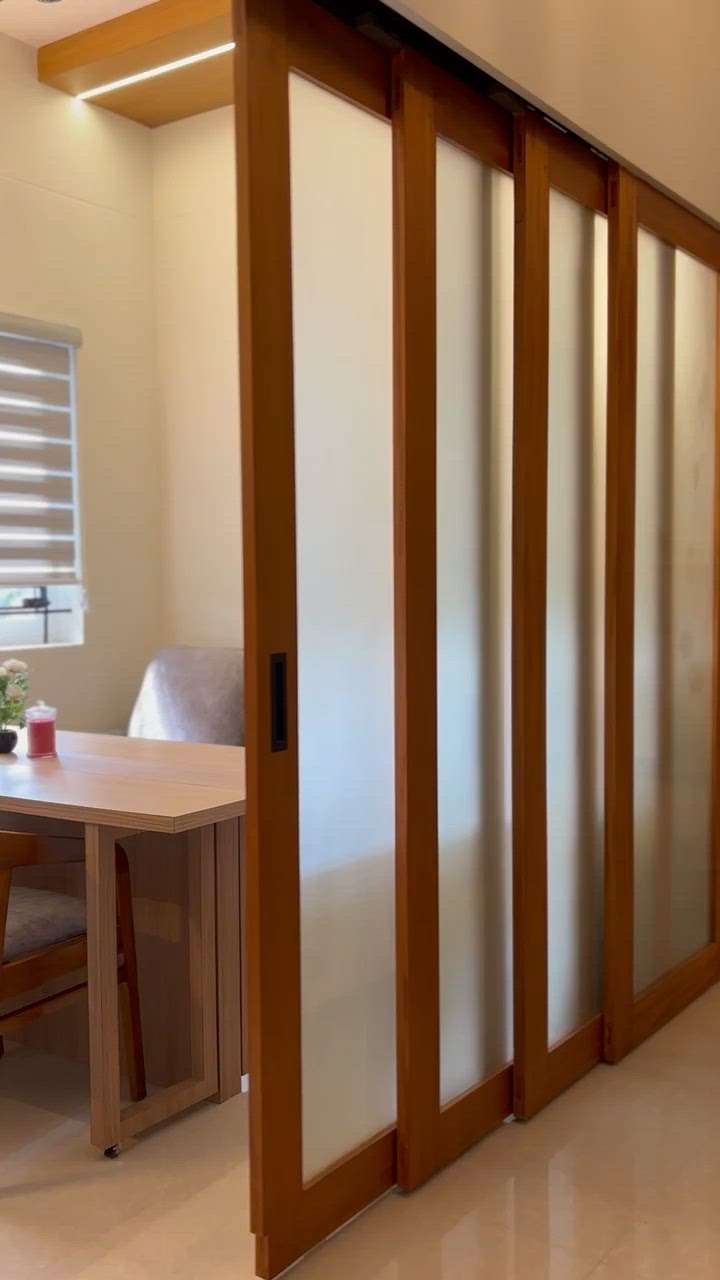 Sliding partition. Dining room with a sofa cum bed and a foldable dining table which helps convert this dining room into a guest room when in need. Top hung sliding fittings from ebco. #small spaces # convertible spaces #privacy frosted glass sliding partition #wood framed glass partition.