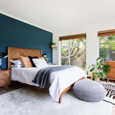 Create warm and cozy bedroom with walls painted in blue which gives a soothing, tranquil vibe. Add in some natural touch with jute planters, live plants, and bamboo roll up shades. Give a wooden finishing to each furniture in the room for an elegant look.#interior #decor #ideas #home #interiordesign #indian #colourful #decorshopping