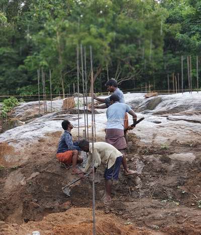 The foundation is being established on a large, uneven rock formation. This requires careful excavation into the soil surrounding the rock and precise planning for the footings to ensure a stable and level base, which is far more demanding than working on uniform, level ground.
 #experienced  #precisecraftsmanship #timelycompletion  #houseinkerala  #KeralaStyleHouse  #Focien