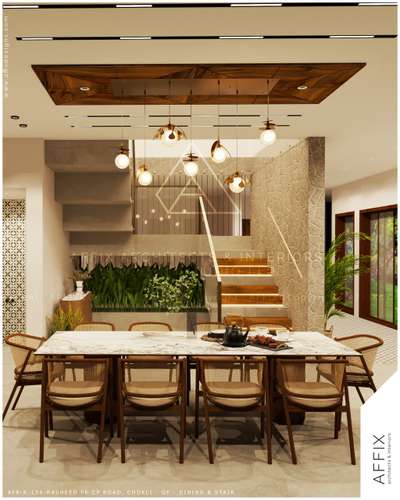 A thoughtfully designed dining space where natural materials and warm lighting take center stage. The marble-top dining table is paired with cane and wood chairs, creating a refined yet inviting setting. Layered pendant lights beneath a wooden ceiling feature add visual warmth, while stone-textured walls, indoor greenery, and a sculptural staircase enhance depth and spatial character. #Architect  #architecturedesigns  #Architectural&Interior  #architectsinkerala  #kerala_architecture  #best_architect  #diningarea  #DiningTableAndChairs  #diningspace