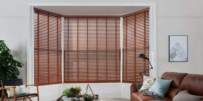 Wooden blinds feature a number of horizontal slats that are linked together by a cord pulley system. This design of the blind is also known as Venetian. When fully raised, the slats gather together at the top of the window, revealing the full view outside. When lowered and rotated, wooden blinds obscure the views from outside and block all sunlight. Wooden blinds can also be arranged in various positions, depending on the amount of privacy and natural light you require.

Wooden blinds are available in a range of finishes. This includes different shades of varnish and stains, matte paint, gloss paint, or a simple wax. You can choose the right finish for your space by considering its functionality, the type of mood you want to evoke, and the other furnishings in the room. If you want to create warm and cozy vibes, a darker shade of varnish will help to set the tone. But if you’re looking to make your home feel lighter, brighter and more fresh, a white or cream painted finish is more suit