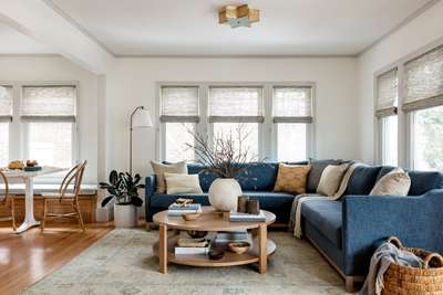 Create this contemporary living room where comfort comes first with this plush and spacious seating, fluffy cushions and a 2-tier wooden coffee table. Use roll up curtains and an abstract rug in gray shade to complete the look. #interior #decor #ideas #home #interiordesign #indian #colourful #decorshopping