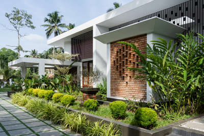 Mridul's Residence at Alappuzha is a four-bedroom single-story house with two courtyards at north and south. Hence, the height is increased to attain a proportionate mass. While sit-out is double height, a circular, open-to-sky glass roofed element is incorporated in the design. This feature acts as a visual focal point and helps create a dynamic composition of rounds and rectangles in the form.
The house is nestled within its natural surroundings, the exterior blending seamlessly with lush landscaping and varied brick patterns. Facing east, carefully placed perforations allow light to stream in.
The projected volume is the pooja room, surrounded by a water body on all sides and well-lit by a skylight. The pattern in longer brick wall brings in the light from the exterior into the inner courtyard. The bedroom and foyer offer a view of the courtyard, providing a sense of connection to the outdoors.

Project Details.
Project Name : Connecting Mango trees
Location : Kappil, alappuzha
Area : 4900 sq.ft.
Photohraphy: @syam.photographer
Completion Year : 2022
Manufacturing & Brands.
Flooring : somany | Q- Tile | Jaisalmer | vitrified Tiles | Ips
Wall cladding : Exposed Brick
Accessories & Interior Fixtures : Hettich India
Light Fixtures : Osram | Ledwell
Kitchen / Wardrobe : Reginox kitchen sinks
Bath fixtures : Kohler India
#cnsbuilders #residentialdesign #kayamkulam #tropicalmodernism #architecturedaily #architectureproject #architecturaldigest #architecturelovers #modernarchitecture #luxurymodern #designkerala #architectsneed