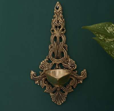 This Jhali hanging is crafted out of Brass and comes with a fine black antique finish. It comes with a single-face diya at the center.
This spectacular piece is a traditional piece of décor that creates a divine ambiance wherever placed. An auspicious choice of gift to your near and dear ones during special occasions or festivals, this stunning wall decor will make an excellent addition to any home, office or shop.

#diya #brassdiya #walldecor #decortwist #decorshopping