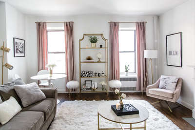 Go for this elegant living room in white-grey theme with touches of blush pink and marble & gold accents. Use long drapes and arm chair in pink shade and fluffy cushions, rugs and furry stool in white shade. Finally add a touch of gold with floor lamp, open glass shelf, coffee table, stool, everything in golden frame. #interior #decor #ideas #home #interiordesign #indian #colourful #decorshopping