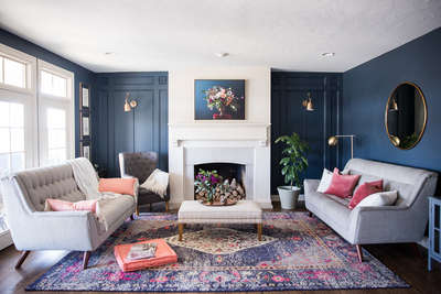 Go for this living room in a gorgeous navy blue that is so chic and sophisticated with a gold rimmed round mirror,golden floor lamp ,a tray decorated with purple flowers in vase and a tufted wing chair in grey.#interior #decor #ideas #home #interiordesign #indian #colourful#decorshopping