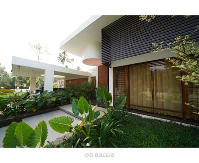 Mridul's Residence at Alappuzha is a four-bedroom single-story house with two courtyards at north and south. Hence, the height is increased to attain a proportionate mass. While sit-out is double height, a circular, open-to-sky glass roofed element is incorporated in the design. This feature acts as a visual focal point and helps create a dynamic composition of rounds and rectangles in the form.
The house is nestled within its natural surroundings, the exterior blending seamlessly with lush landscaping and varied brick patterns. Facing east, carefully placed perforations allow light to stream in.
The projected volume is the pooja room, surrounded by a water body on all sides and well-lit by a skylight. The pattern in longer brick wall brings in the light from the exterior into the inner courtyard. The bedroom and foyer offer a view of the courtyard, providing a sense of connection to the outdoors.

Project Details.
Project Name : Connecting Mango trees
Location : Kappil, alappuzha
Area : 4900 sq.ft.
Photohraphy: @syam.photographer
Completion Year : 2022
Manufacturing & Brands.
Flooring : somany | Q- Tile | Jaisalmer | vitrified Tiles | Ips
Wall cladding : Exposed Brick
Accessories & Interior Fixtures : Hettich India
Light Fixtures : Osram | Ledwell
Kitchen / Wardrobe : Reginox kitchen sinks
Bath fixtures : Kohler India
#cnsbuilders #residentialdesign #kayamkulam #tropicalmodernism #architecturedaily #architectureproject #architecturaldigest #architecturelovers #modernarchitecture #luxurymodern #designkerala #architectsneed