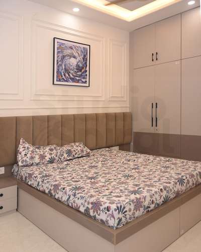 After a long day, you step into this bedroom and instantly feel at ease—it quietly says, “welcome home.” 
The ribbed fabric headboard feels soft and inviting, perfect for late-night reading or quiet reflection. Beneath it, a smooth light-wood bed with hidden storage keeps the room calm and clutter-free. A vibrant abstract artwork pops against crisp white paneling, adding life and personality. To the side, a custom wardrobe in matte cream with deep neutral accents blends style with practicality. The whole space feel warm, modern, and deeply comforting—a true personal sanctuary.
.
.
#architucture #interiordesign #IndianInteriors #JaipurDesign #ModernIndianHomes #InteriorDesignIndia #IndianLuxuryHomes #LuxuryInteriors #ElegantLiving #ArchitectureIndia #ArchitectLife #ContemporaryArchitecture #DesignCommunity #InteriorInspiration #DreamBedroom #SereneSpaces #ModernElegance #StyledSpaces #clutterfreeliving