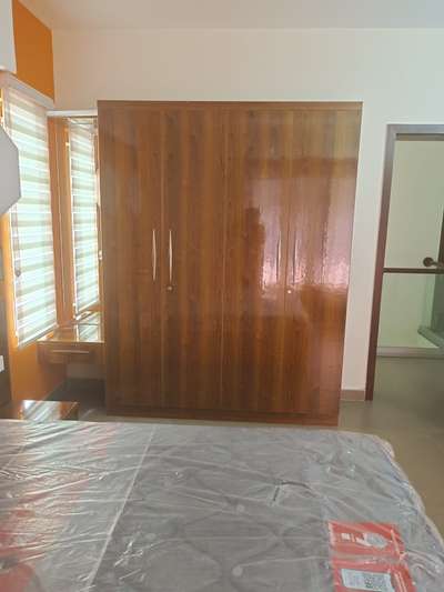 Featuring sleek glossy laminates, this wardrobe with a dressing table near the window adds a touch of elegance to our villa project