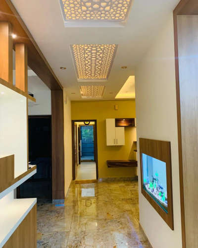 This elegant space, designed by Evolve Interiocrat, features a glossy marble hallway with backlit, intricately patterned ceiling panels, wooden accents, and a built-in aquarium for a serene atmosphere 💕 🌌 

The sophisticated bathroom vanity area showcases a rustic stone tile feature wall, dual white basins on sleek black countertops, and a uniquely shaped, LED-backlit mirror, blending natural and modern elements seamlessly 🪄

#luxuryliving
#interiordesignexcellence
#timelesselegance
#innovativedesign
#dreamhome
#interiorinspiration
#homedecor
#craftsmanship
#designgoals
#interiordecor
#homedesign
#creatingbeautifulspaces
#styleandsubstance
#highendliving
#masterpiece
#creativespaces
#modernluxury
#elegantinteriors