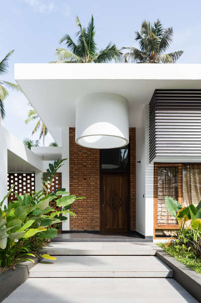 Mridul's Residence at Alappuzha is a four-bedroom single-story house with two courtyards at north and south. Hence, the height is increased to attain a proportionate mass. While sit-out is double height, a circular, open-to-sky glass roofed element is incorporated in the design. This feature acts as a visual focal point and helps create a dynamic composition of rounds and rectangles in the form.
The house is nestled within its natural surroundings, the exterior blending seamlessly with lush landscaping and varied brick patterns. Facing east, carefully placed perforations allow light to stream in.
The projected volume is the pooja room, surrounded by a water body on all sides and well-lit by a skylight. The pattern in longer brick wall brings in the light from the exterior into the inner courtyard. The bedroom and foyer offer a view of the courtyard, providing a sense of connection to the outdoors.

Project Details.
Project Name : Connecting Mango trees
Location : Kappil, alappuzha
Area : 4900 sq.ft.
Photohraphy: @syam.photographer
Completion Year : 2022
Manufacturing & Brands.
Flooring : somany | Q- Tile | Jaisalmer | vitrified Tiles | Ips
Wall cladding : Exposed Brick
Accessories & Interior Fixtures : Hettich India
Light Fixtures : Osram | Ledwell
Kitchen / Wardrobe : Reginox kitchen sinks
Bath fixtures : Kohler India
#cnsbuilders #residentialdesign #kayamkulam #tropicalmodernism #architecturedaily #architectureproject #architecturaldigest #architecturelovers #modernarchitecture #luxurymodern #designkerala #architectsneed