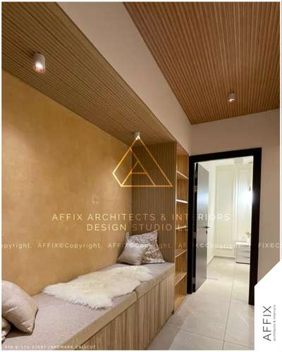 Earthy elegance meets modern minimalism. This cozy nook combines warm beige textures with natural wooden accents, creating a seamless blend of comfort and sophistication. The fluted wood ceiling and textured walls add depth, while soft lighting enhances the ambiance. Perfectly crafted for relaxation. #Architect  #architecturedesigns  #Architectural&Interior  #architectsinkerala  #kerala_architecture  #best_architect